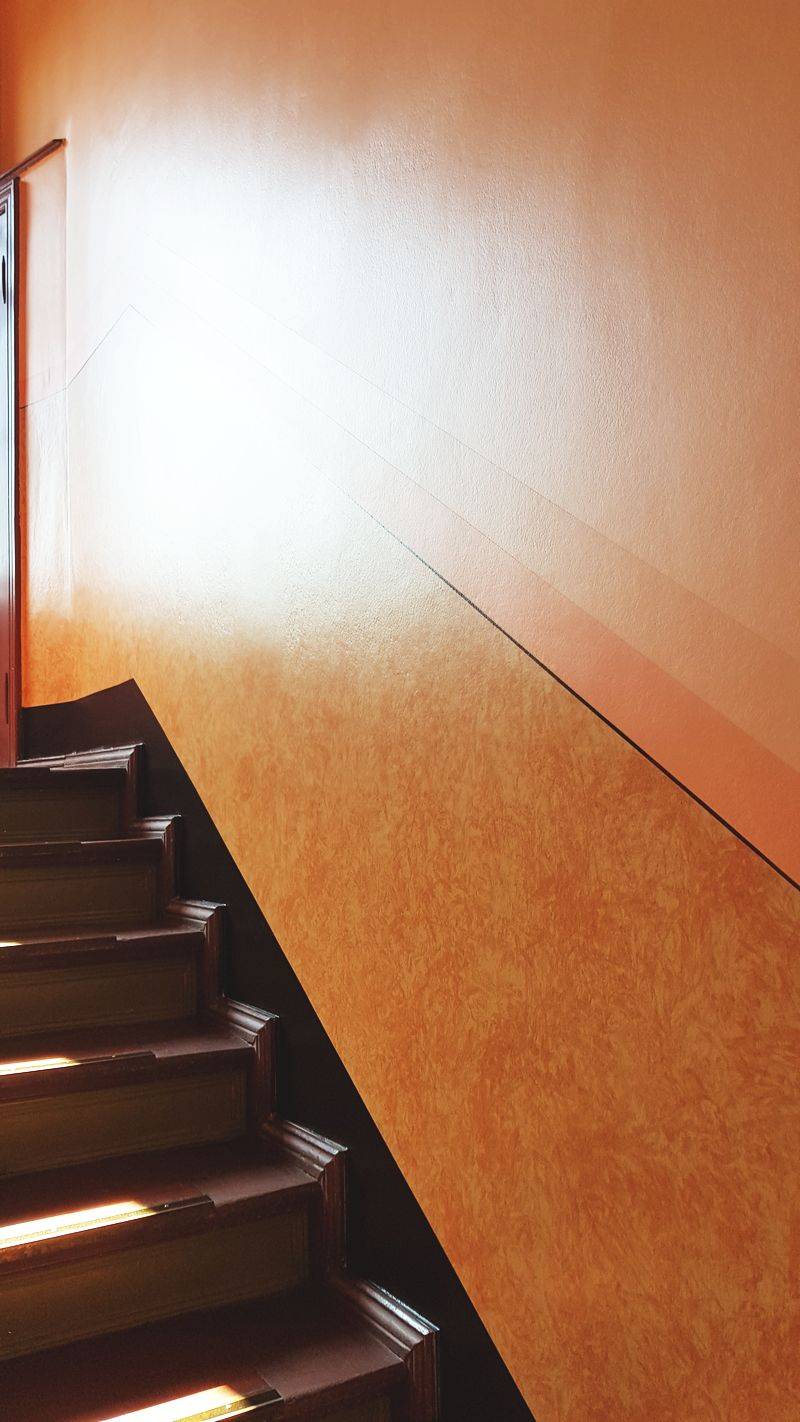 X Wickeltechnik in einem Treppenhaus in Berlin Friedrichshagen. Das Haus aus der Gründerzeit wurde in seiner Ausmalung aus den 30iger Jahren rekonstruiert. Die Wickeltechnik wurde als Lasur angelegt und hat somit sehr viel tiefe. Als Material wurde Ölfarbe gewählt. Diese ist wesentlich haltbarer als polymere Lacke. Eine Wickeltechnik kaschiert Unebenheiten und kleinere Beschädigungen. Farben mit Glanzgrad, der sich auch auf der Oberwand wiederfindet, ist stabiler als matte Farbsysteme. Auf der Oberwand wurde eine Emulsion verwendet. Diese hat eine deutlich höhere Haltbarkeit als herkömmliche Dispersionsfarbe. Durch die vielen Erfahrungen am Denkmal und die gute Aufstellung der Firma restaurierung & gestaltung mit einem Malermeister, staatl. geprüfter Techniker, Malern und einem Restaurator im Handwerk sind schon viele Treppenhäuser zur Zufriedenheit der Kundschaft überarbeitet worden. Die Kombination aus Maler, Malermeister und Restaurator ist das Fundament des Unternehmens und stellt hohe Qualität kostenneutral sicher.